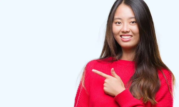 分離背景手と カメラ目線の顔に幸せで自然な表現のある側までの指で指している顔の笑顔で元気に冬のセーターを着た若いアジア女性 — ストック写真