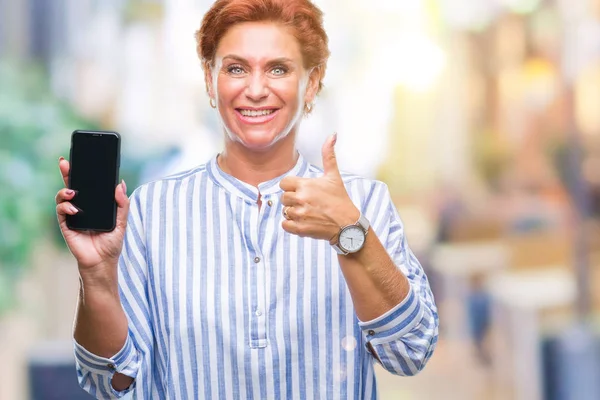 笑顔の サイン 優秀な兆候を親指をやって幸せな背景を分離館シニアの白人赤毛の女性にスマート フォンの画面を表示 — ストック写真