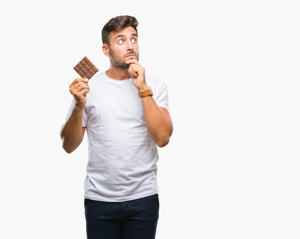 Όμορφος Νεαρός Τρώει Σοκολάτα Πέρα Από Απομονωμένο Φόντο Σοβαρό Πρόσωπο — Φωτογραφία Αρχείου