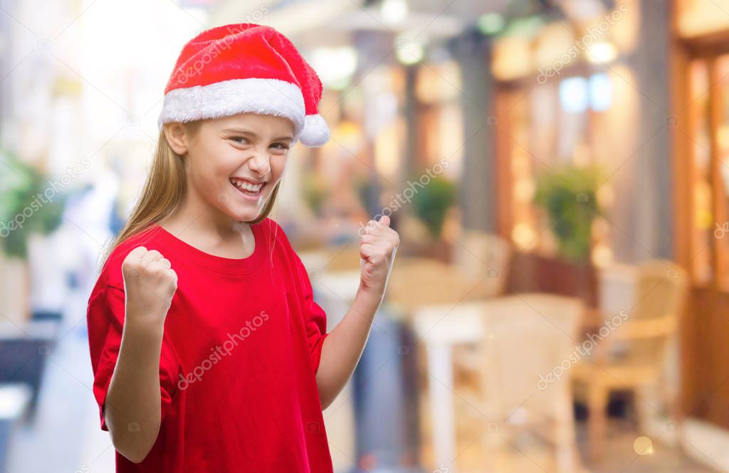 Young beautiful girl wearing christmas hat over isolated background very happy and excited doing winner gesture with arms raised, smiling and screaming for success. Celebration concept.