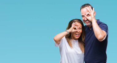 Orta yaş İspanyol rahat çift el gülümseyen, ok jest yapıyor izole arka plan üzerinde göz parmakları ile mutlu yüz üzerinden seyir.