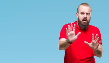 Üzerinde kırmızı gömlek giyen genç beyaz hipster adam arka plan korkuyor ve korku ifade dur hareketi el ile ile dehşete şokta bağırarak izole. Panik kavramı.