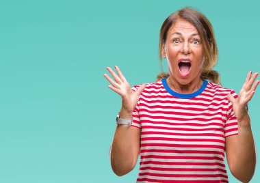 Orta yaş üst düzey İspanyol kadın deli kutluyor arka plan izole ve başarı için kaldırdı kollarını açarak hayrete ve heyecanlı çığlık gözleri açık. Kazanan kavramı