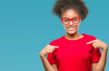 Yüzünde gülümseme ile kendinden emin görünüyorsun, kendini gururlu ve mutlu parmakları ile işaret izole arka plan üzerinde gözlük takan genç afro Amerikalı kadın.