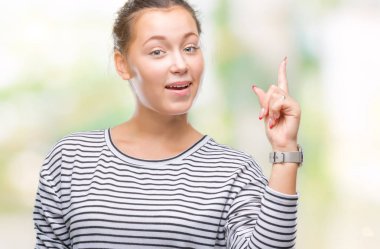 Genç güzel beyaz kadın başarılı fikirle parmağı yukarıyı izole arka plan yüzünden. Çıktıktan ve mutlu. Bir numara.