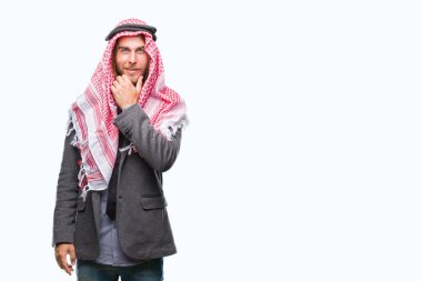 Genç yakışıklı Arap adam uzun saçlı emin çapraz kollar ve çeneme kaldırdı el ile gülümseme ile kameraya bakarak izole arka plan üzerinde keffiyeh giyiyor. Pozitif düşünce.