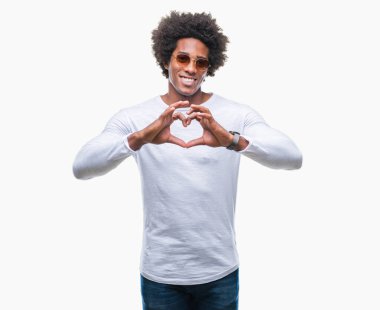 Afro Amerikalı adam aşık kalp simgesi ve elleriyle şekil gösteren gülümseyen izole arka plan üzerinde güneş gözlüğü takıyor. Romantik kavramı.