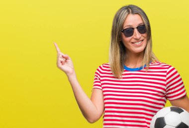 Futbol futbol topu izole arka plan üzerinde çok mutlu el ve parmak ile tarafına işaret tutan genç güzel kadın