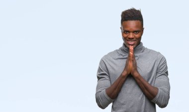 İzole arka plan birlikte emin gülümseyen bağışlanmak ellerle dua genç Afro-Amerikan adam.