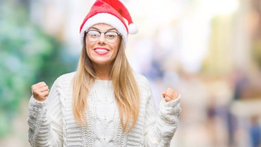 İzole arka plan kutlama üzerinde Noel şapka giyen genç güzel kadın şaşırttı ve başarı için kaldırdı kollarını açarak hayret ve gözleri açık. Kazanan kavramı.