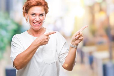 Atrractive üst düzey beyaz Kızıl saçlı kadın gülümseyerek ve iki elleri ve parmakları ile tarafına işaret kamera bakarak izole arka plan.