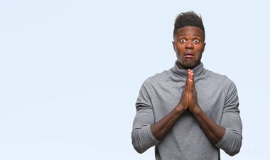 Afrikalı-Amerikalı genç yalvarıyor ve umut ifade yüzünde çok duygusal ve endişe ile birlikte elleriyle dua izole arka plan üzerinde. Bağışlanmak. Din kavramı.