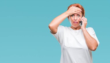 Atrractive üst düzey beyaz Kızıl saçlı kadın baş, el ile vurguladı izole arka plan üzerinde Smartphone'da söz şok utanç ve sürpriz suratla, öfkeli ve sinirli. Korku ve hata için üzgün.