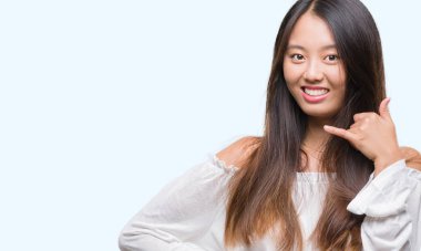 Genç Asyalı kadın yapıyor gülümseyen izole arka plan üzerinde telefon hareketi ile el ve parmak telefonda konuşuyor gibi. Kavramları iletişim.