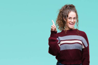 Güzel esmer kıvırcık saçlı Genç kız ve parmak gülümseyen süre bir numara ile kendinden emin ve mutlu yukarıyı gösteren izole arka plan üzerinde gözlük.