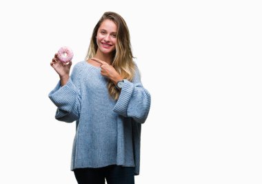 Genç güzel sarışın kadın izole arka el ve parmak ile işaret çok mutlu üzerinde tatlı çörek yeme