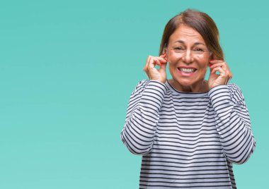 Orta yaş İspanyol kadın kıdemli yüksek sesle müzik gürültü rahatsız ifade parmaklarıyla kulaklarıyla kapsayan izole arka plan üzerinde. Sağır kavramı.