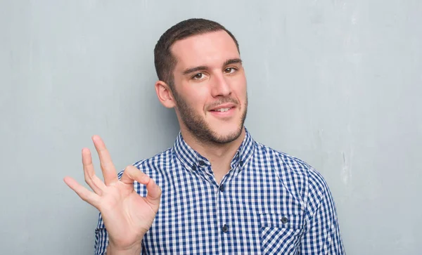 Joven Caucásico Hombre Sobre Gris Grunge Pared Haciendo Signo Con —  Fotos de Stock