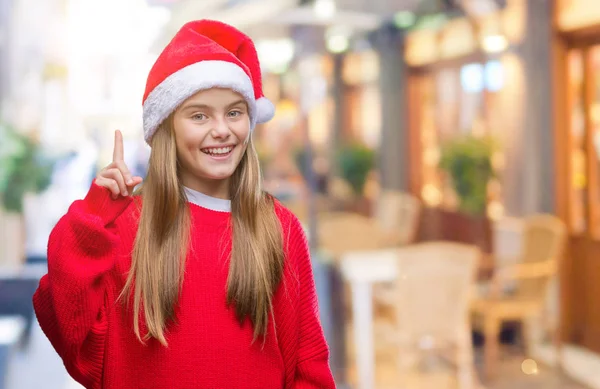 分離背景表示と指番号のいずれかニコニコしながら自信を持って 幸せを上向きにクリスマスの帽子を着た美しい少女 — ストック写真