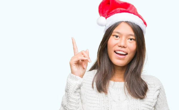 Молода Азіатка Носить Різдвяний Капелюх Над Ізольованим Тлом Вказуючи Пальцем — стокове фото
