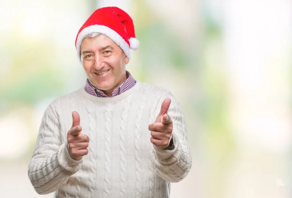 ハンサムな年配の男性は 幸せと面白い顔でカメラに指を指して孤立の背景にクリスマス帽子をかぶっています 良いエネルギーとヴァイブス — ストック写真