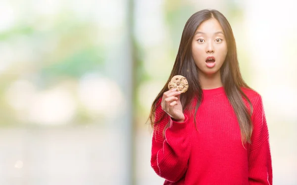 驚き顔 恐怖表現と興奮とショックで怖い孤立の背景の上のチョコレート チップ クッキーを食べる若いアジア女性 — ストック写真