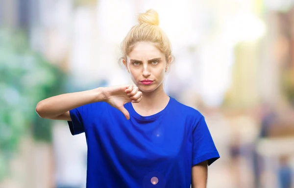 Young beautiful blonde and blue eyes woman wearing blue t-shirt over isolated background looking unhappy and angry showing rejection and negative with thumbs down gesture. Bad expression.