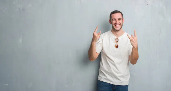 Joven Hombre Caucásico Sobre Pared Gris Grunge Usando Gafas Sol —  Fotos de Stock