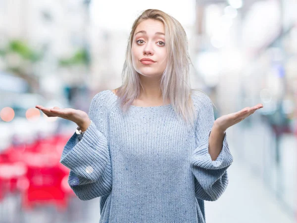 年轻的金发女子穿着冬季毛衣在孤立的背景无能和混淆表达与胳膊和手提出 怀疑概念 — 图库照片