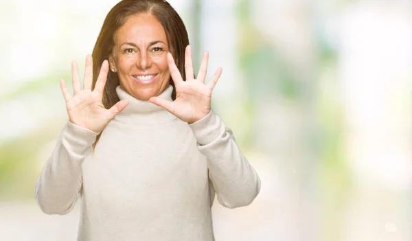 上冬のセーターを着て美しい中年成人女性分離を示す背景と自信を持って 幸せな笑みを浮かべている間 番号を指で上向き — ストック写真