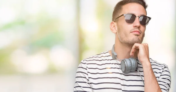 Joven Guapo Usando Auriculares Con Mano Barbilla Pensando Pregunta Expresión —  Fotos de Stock