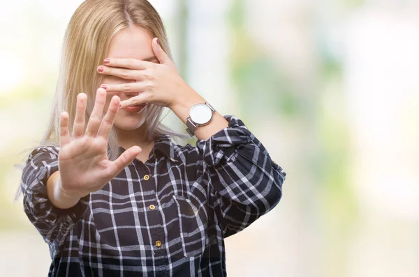 Young blonde woman over isolated background covering eyes with hands and doing stop gesture with sad and fear expression. Embarrassed and negative concept.