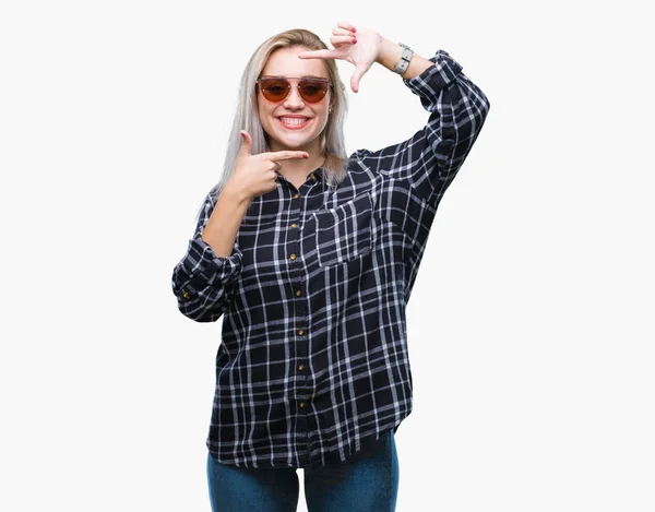 若いブロンドの女性は 笑顔と幸せそうな顔で指手作りフレーム分離の背景の上にサングラスをかけています 創造性と写真のコンセプト — ストック写真