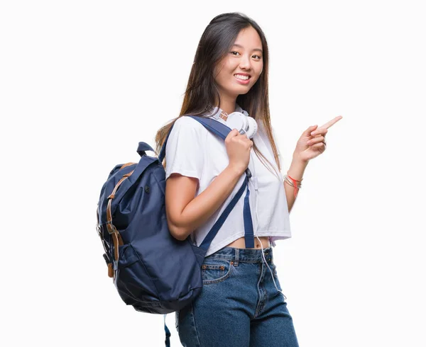 Молодая Азиатская Женщина Рюкзаке Наушниках Изолированном Фоне Счастлива Указывая Рукой — стоковое фото