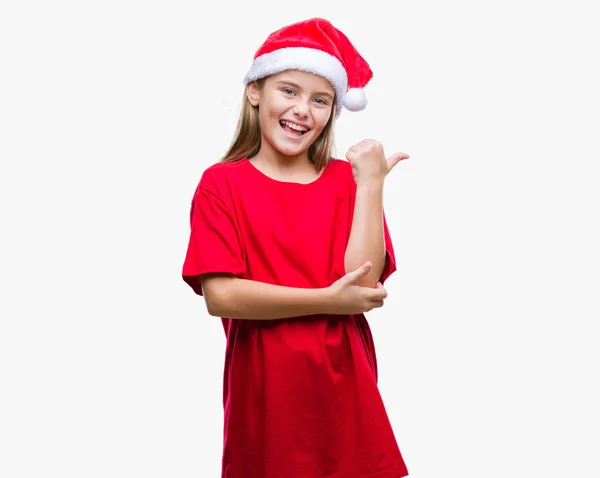 年轻美丽的女孩戴着圣诞节帽子在孤立的背景微笑与快乐的脸看和指向侧与拇指向上 — 图库照片