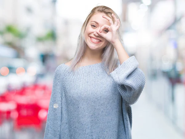 年轻的金发女子穿着冬季毛衣在孤立的背景做 手势与手微笑 眼睛看通过手指与幸福的脸 — 图库照片