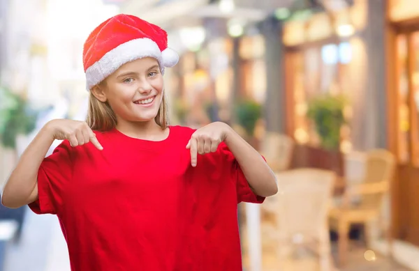 美しい少女の顔に笑顔と自信を持って 誇りと幸せな指で自分を指している孤立した背景にクリスマスの帽子をかぶって — ストック写真