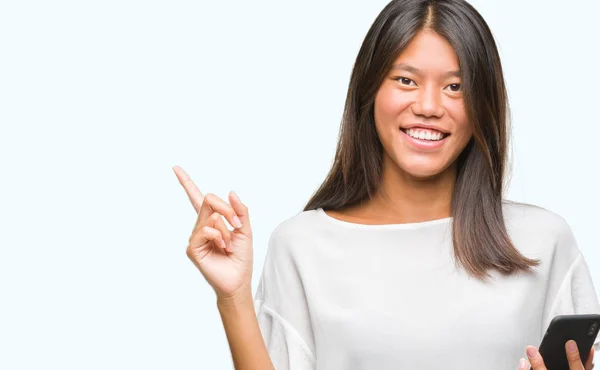 年轻的亚洲妇女发短信使用智能手机在孤立的背景下非常高兴地指着手和手指的侧面 — 图库照片