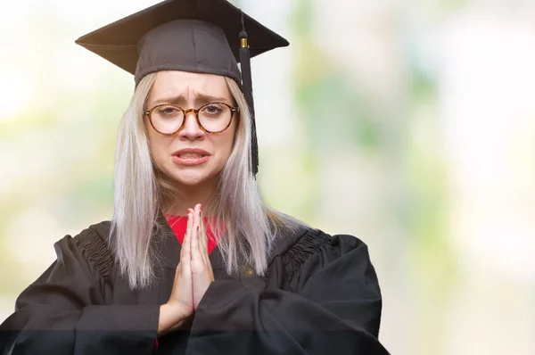 若いブロンドの女性は 懇願するような非常に感情的なおよび心配の顔希望表現とともに手で祈って分離の背景の上の大学院の制服を着ています 赦しを乞います 宗教概念 — ストック写真