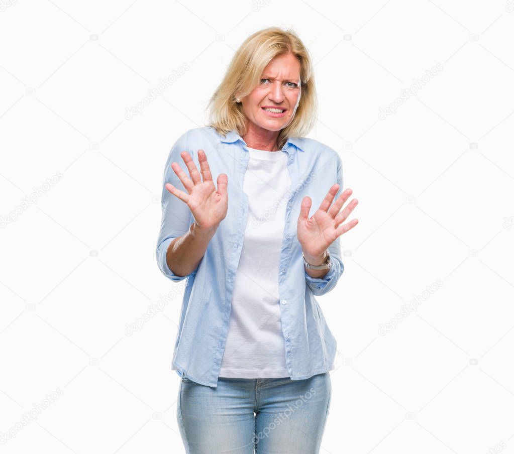 Middle age blonde woman over isolated background disgusted expression, displeased and fearful doing disgust face because aversion reaction. With hands raised. Annoying concept.