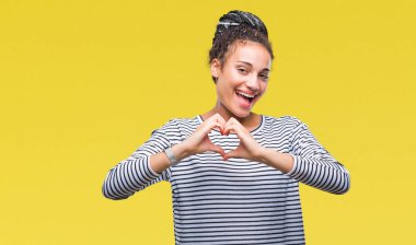 Genç örgülü saç Afro-Amerikan kız aşık kalp simgesi ve elleriyle şekil gösteren gülümseyen izole arka plan üzerinde kazak giyiyor. Romantik kavramı.