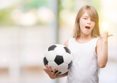 Genç Sarışın yürümeye başlayan çocuk el ve parmak ile yukarı dönük mutlu yüz gülümseyen ile futbol topu tutan