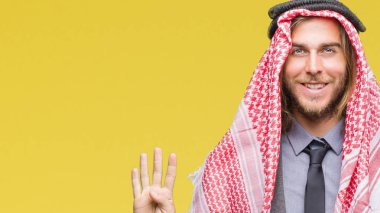 Genç yakışıklı Arap adam uzun saçlı keffiyeh gösterilen ve parmakları ile işaret izole arka plan üzerinde giyen süre kendinden emin ve mutlu gülümseyerek dört numara.