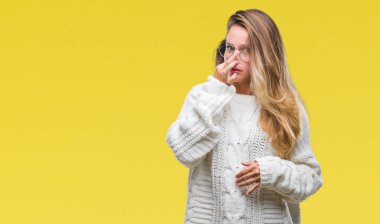 Kış kazak ve güneş gözlüğü takan bir şey pis ve iğrenç kokulu izole arka plan, dayanılmaz koku, holding nefes burun parmaklar ile genç güzel sarışın bir kadın. Kötü kokuyor kavramı.