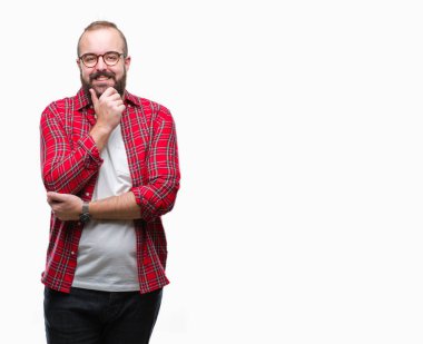 Emin çapraz kollar ve çeneme kaldırdı el ile gülümseme ile kameraya bakarak izole arka plan üzerinde gözlük takan Genç beyaz hipster adam. Pozitif düşünce.