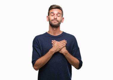 Yakışıklı delikanlı ile gülümseyen izole arka plan üzerinde kış kazak giyen kapalı gözler ve yüzünde minnettar jest ile göğüs üzerinde eller. Sağlık kavramı.