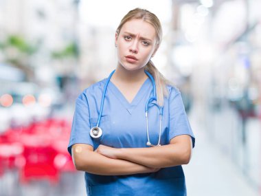 Genç Sarışın cerrah doktor kadın izole arka plan şüpheci ve çapraz kolları olan yüzündeki gergin, onaylamayan ifade yüzünden. Negatif kişi.