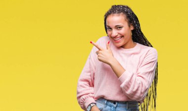 Genç izole arka neşeli bir gülümseme ile el ve parmak kadar kameraya bakarak yüzündeki mutlu ve doğal ifade ile yan ile işaret yüz üzerinden kazak giyen saç Afro-Amerikan Kız örgülü.