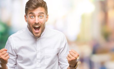 İzole arka plan kutlama üzerinde genç yakışıklı adam şaşırttı ve başarı için kaldırdı kollarını açarak hayret ve gözleri açık. Kazanan kavramı.