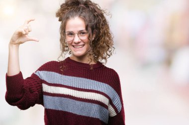 Güzel esmer kıvırcık saçlı Genç kız gözlük gülümseyen izole arka plan ve boyutu işaret parmaklı ararken ve kamera işi el ile kendinden emin eller üzerinde. Ölçü kavramı.